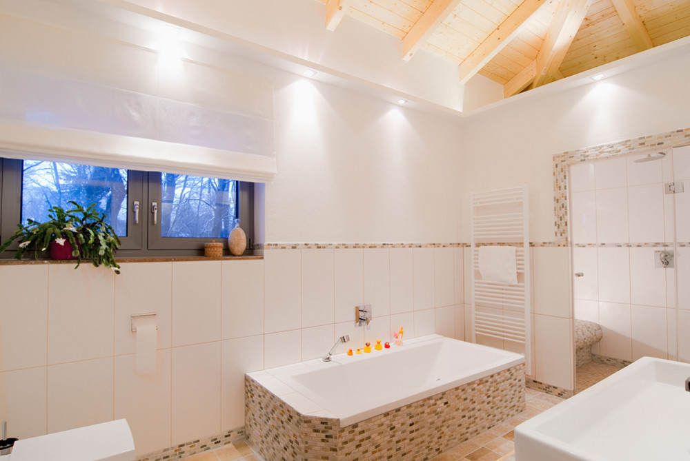 Modernes, helles Badezimmer mit Badewanne, Dusche, Fenster und dekorativer Pflanze. Entspannende Atmosphäre.