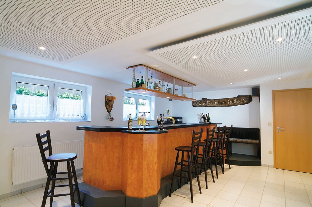 Gemütliche Bar mit hölzerner Theke, hohen Barhockern und Flaschen, in warmem, einladendem Ambiente.